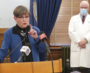 Kansas Gov. Laura Kelly discusses the coronavirus pandemic as her health secretary, Dr. Lee Norman, watches behind her at a news conference, Tuesday, Nov. 10, 2020, at the Statehouse in Topeka, Kan. Kelly says the state's unified strategy for more aggressive testing won't work to curb the spread of the virus if people don't wear face masks and socially distance. (AP Photo/John Hanna)